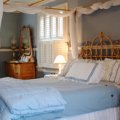 Lovejoy Suite - This gracious room is accented in shades of blue.  The antiqued queen size canopy bed and chaise, attached sitting room with TV. VCR, French windows, oak floors writing table plus a commanding view of all the grounds is truly a delight. The private bath includes a restored claw foot soaking tub, just a perfect way to end a day. One Queen size bed with a private claw foot bath and shower, with air-conditioning.